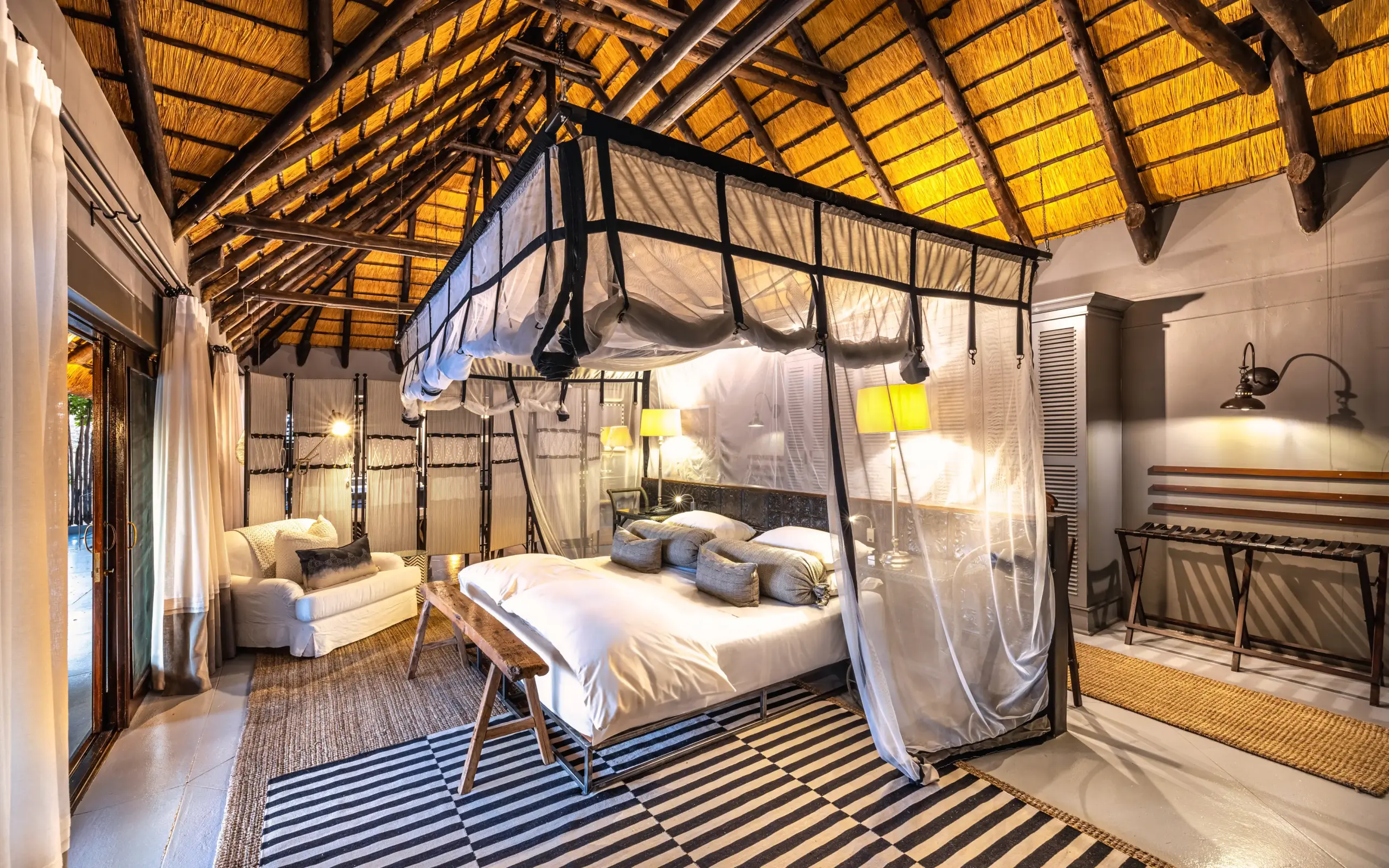 Luxury safari bedroom with four-poster canopy bed and thatch roof interior, Villa Mushara, Etosha National Park, Namibia