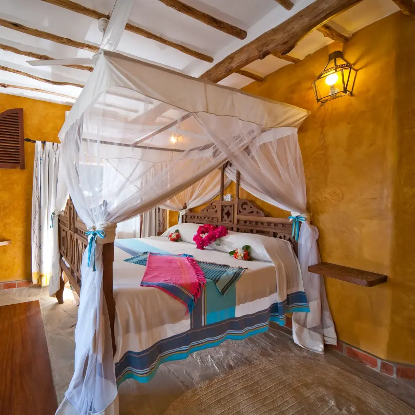 Spacious bedroom with canopy bed and golden ochre walls, Waterlovers Beach Resort, Diani Beach, Kenya