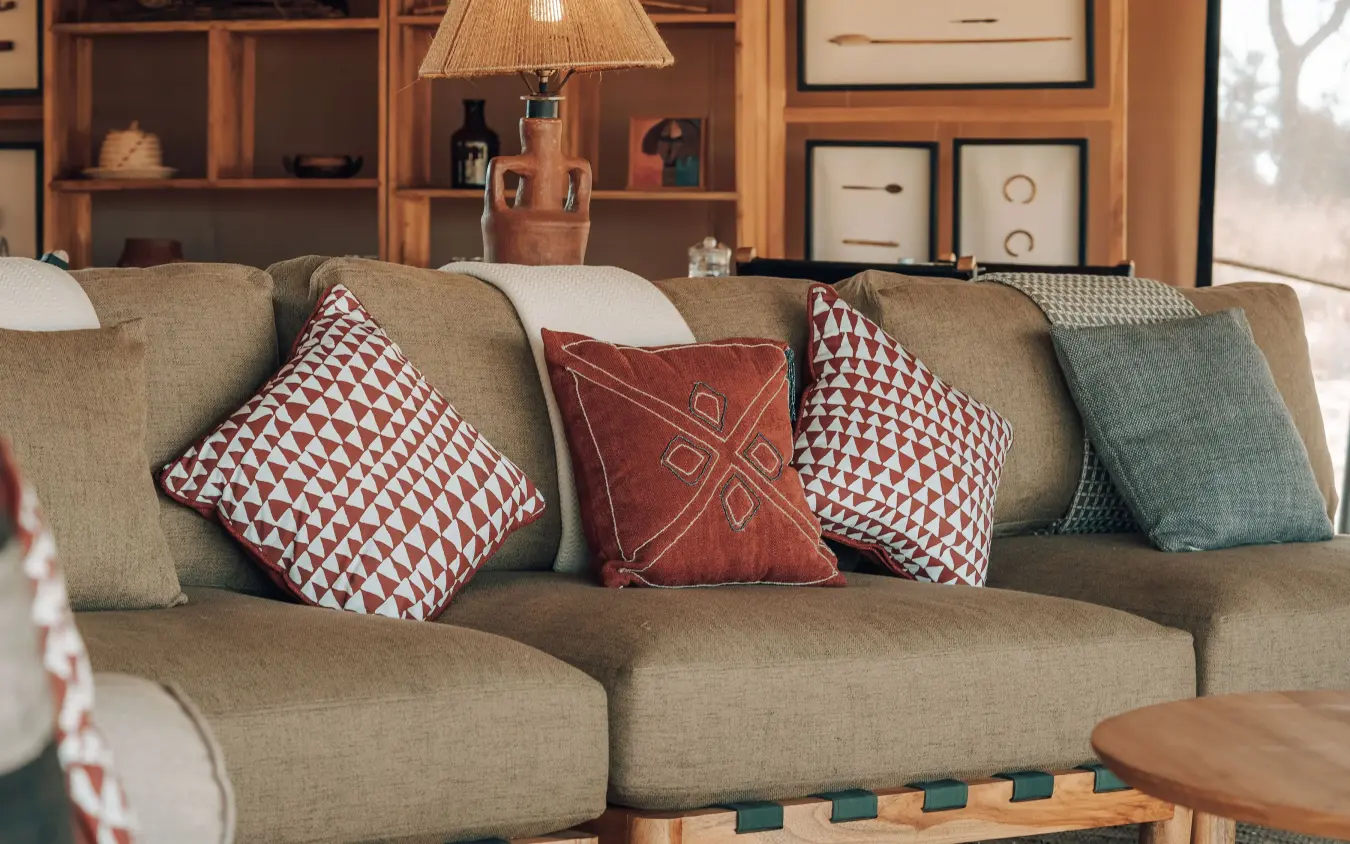 Beige sofa with patterned throw pillows and wooden shelving, Serengeti Green Camp, Serengeti National Park, Tanzania
