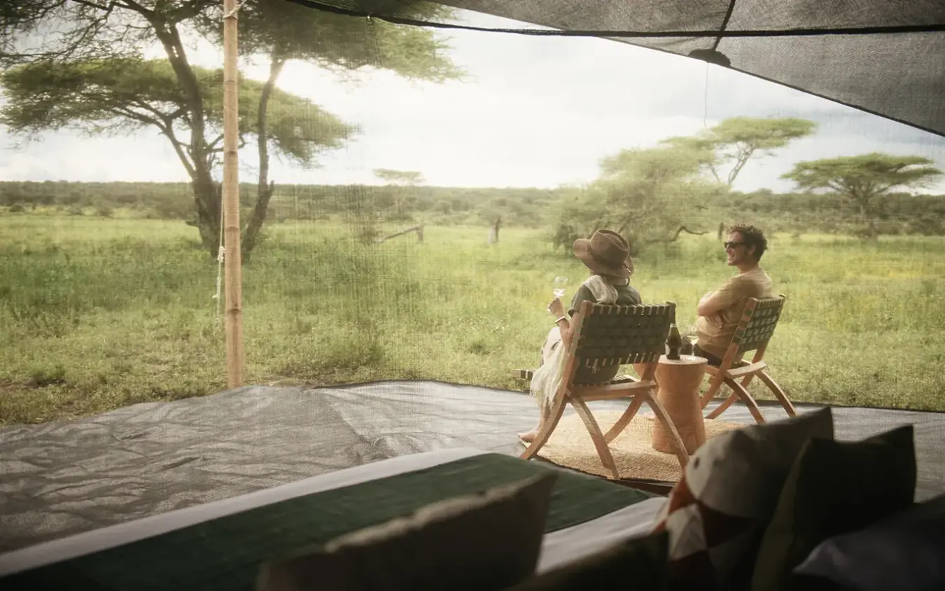 Guests relax on deck chairs viewing savanna landscape, Serengeti Green Camp, Serengeti National Park, Tanzania