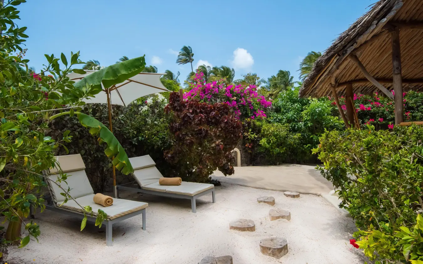 Sandy terrace with loungers, umbrellas, and flowering plants, White Sand Luxury Villas & Spa, Zanzibar & Pemba, Tanzania