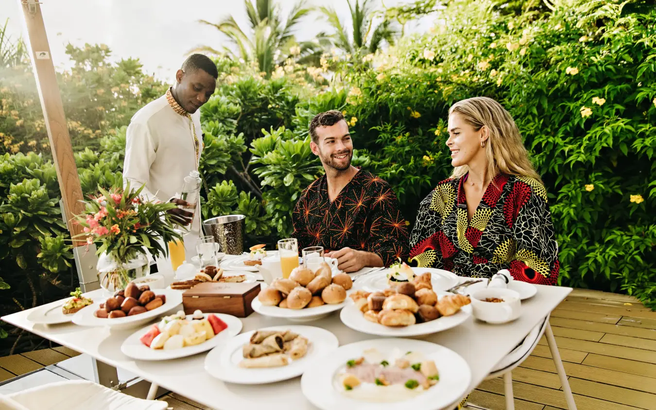 Three guests enjoying meal at outdoor table surrounded by greenery, White Sand Luxury Villas & Spa, Zanzibar & Pemba, Tanzania