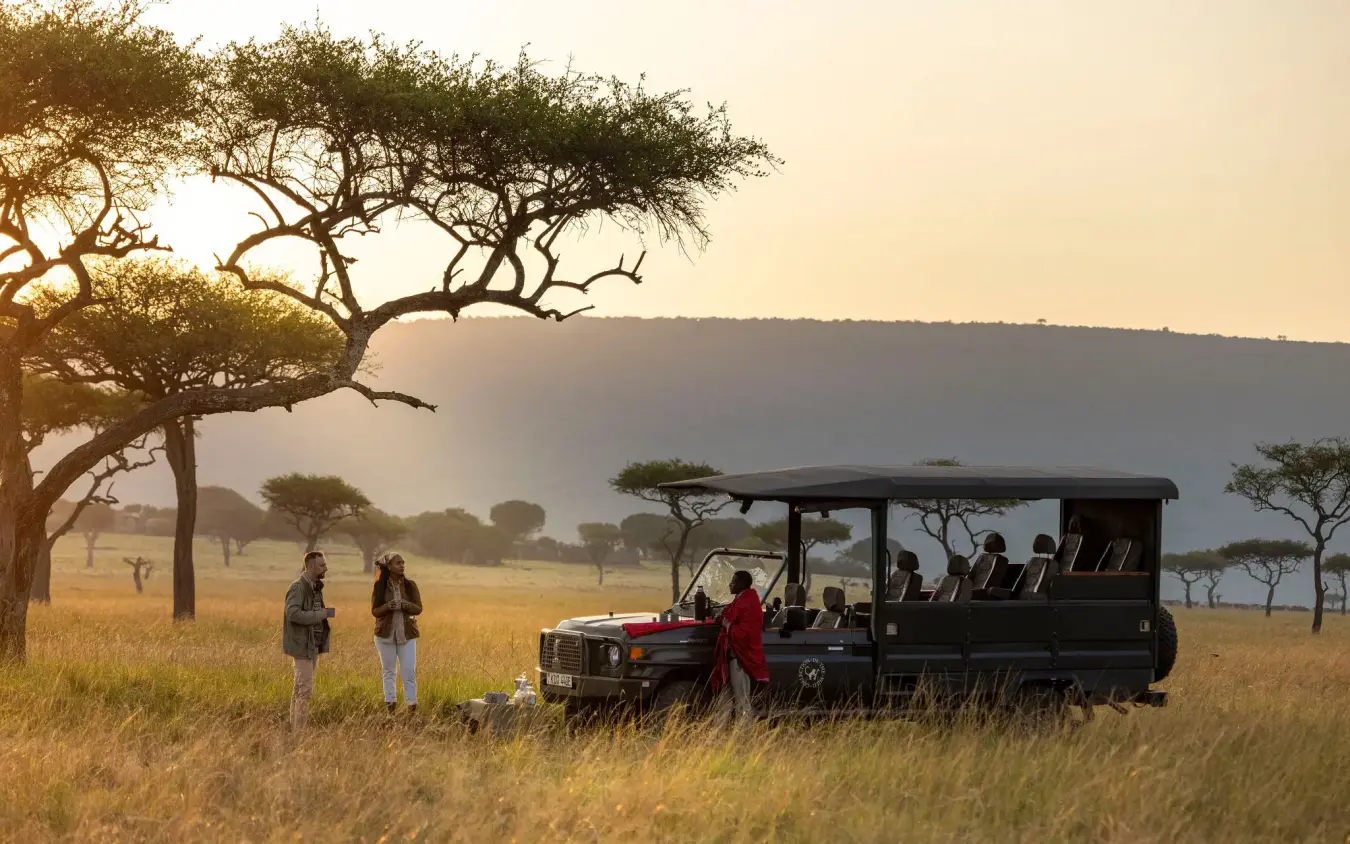 Safari vehicle with guests observing wildlife at golden hour, Wild Hill, Maasai Mara, Kenya
