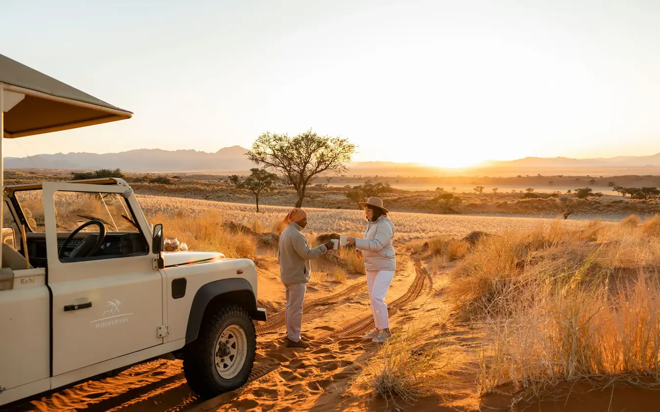 Guides preparing refreshments during golden hour safari, Wolwedans Boulders Camp, NamibRand Private Reserve, Namibia