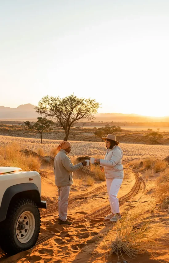 Guides preparing refreshments during golden hour safari, Wolwedans Boulders Camp, NamibRand Private Reserve, Namibia