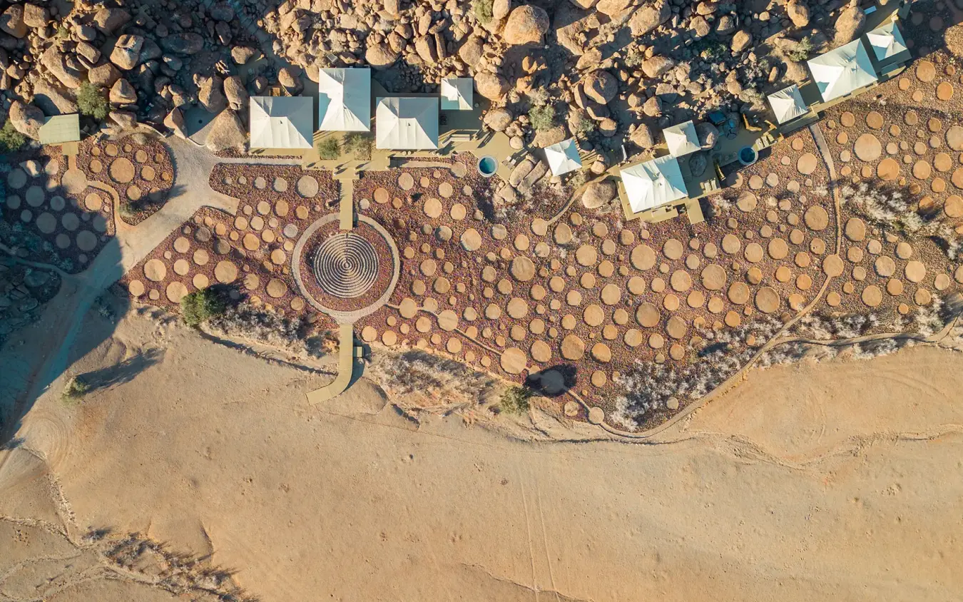 Aerial view of desert lodge with circular water tank and buildings, Wolwedans Boulders Camp, NamibRand Private Reserve, Namibia