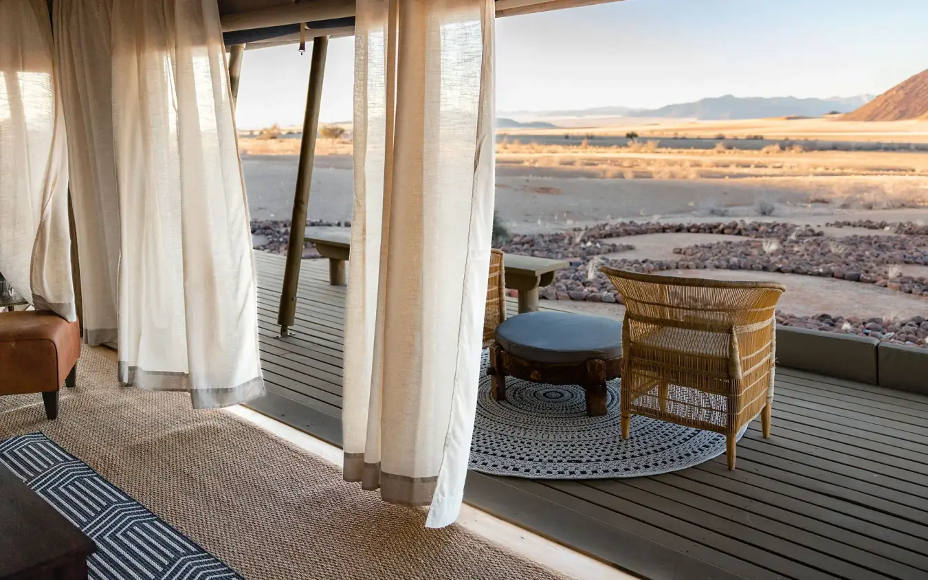 Private deck with chairs overlooking expansive desert landscape, Wolwedans Boulders Camp, NamibRand Private Reserve, Namibia