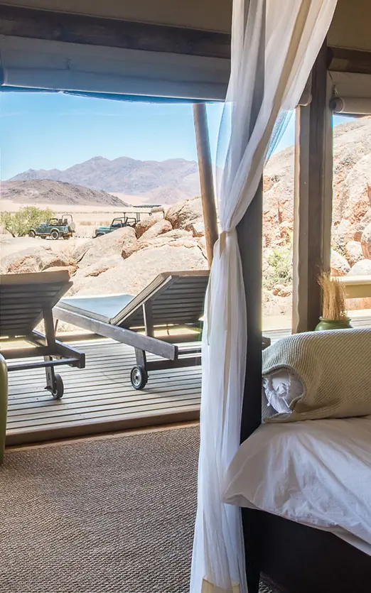 Bedroom with expansive windows overlooking desert landscape, Wolwedans Boulders Camp, NamibRand Private Reserve, Namibia
