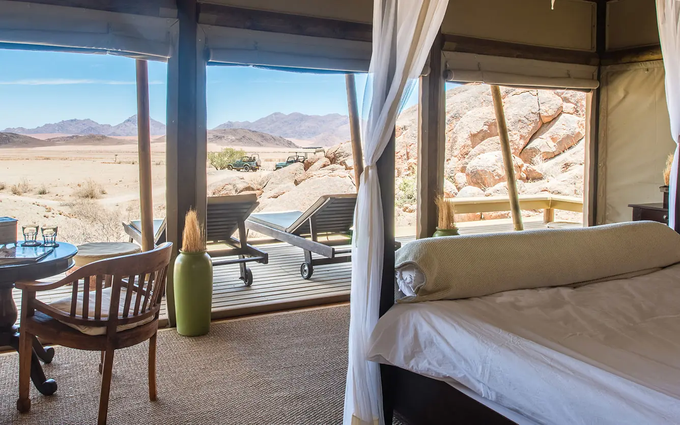 Bedroom with expansive windows overlooking desert landscape, Wolwedans Boulders Camp, NamibRand Private Reserve, Namibia