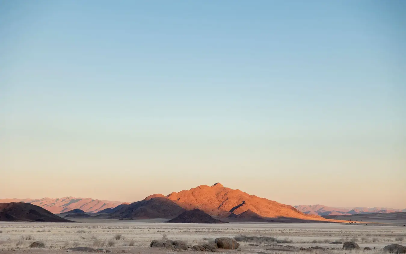 Desert mountain landscape at golden hour with sparse vegetation, Wolwedans Boulders Camp, NamibRand Private Reserve, Namibia