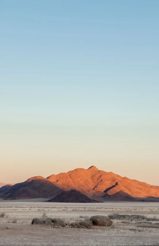 Desert mountain landscape at golden hour with sparse vegetation, Wolwedans Boulders Camp, NamibRand Private Reserve, Namibia