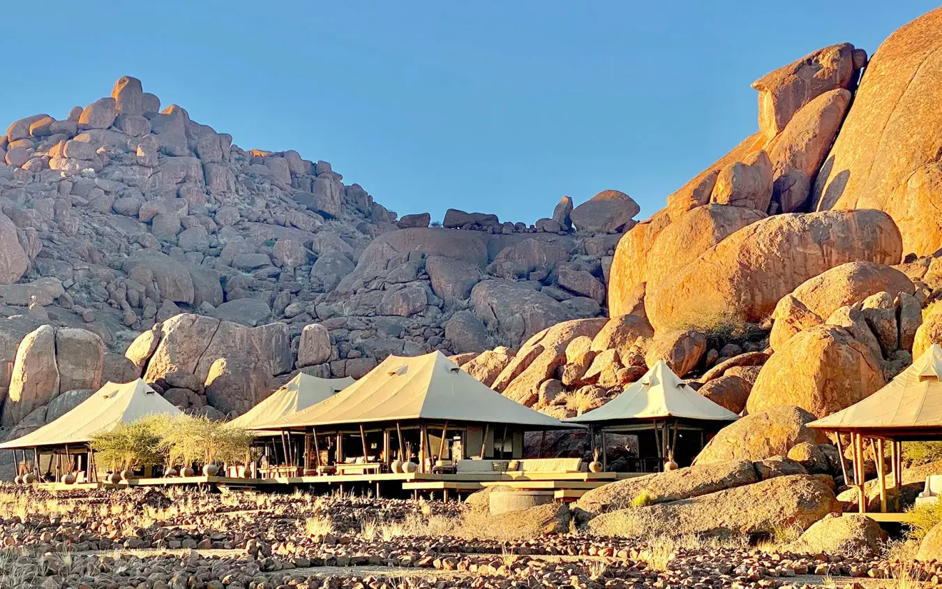 Canvas tents nestled among massive granite boulders at dusk, Wolwedans Boulders Camp, NamibRand Private Reserve, Namibia
