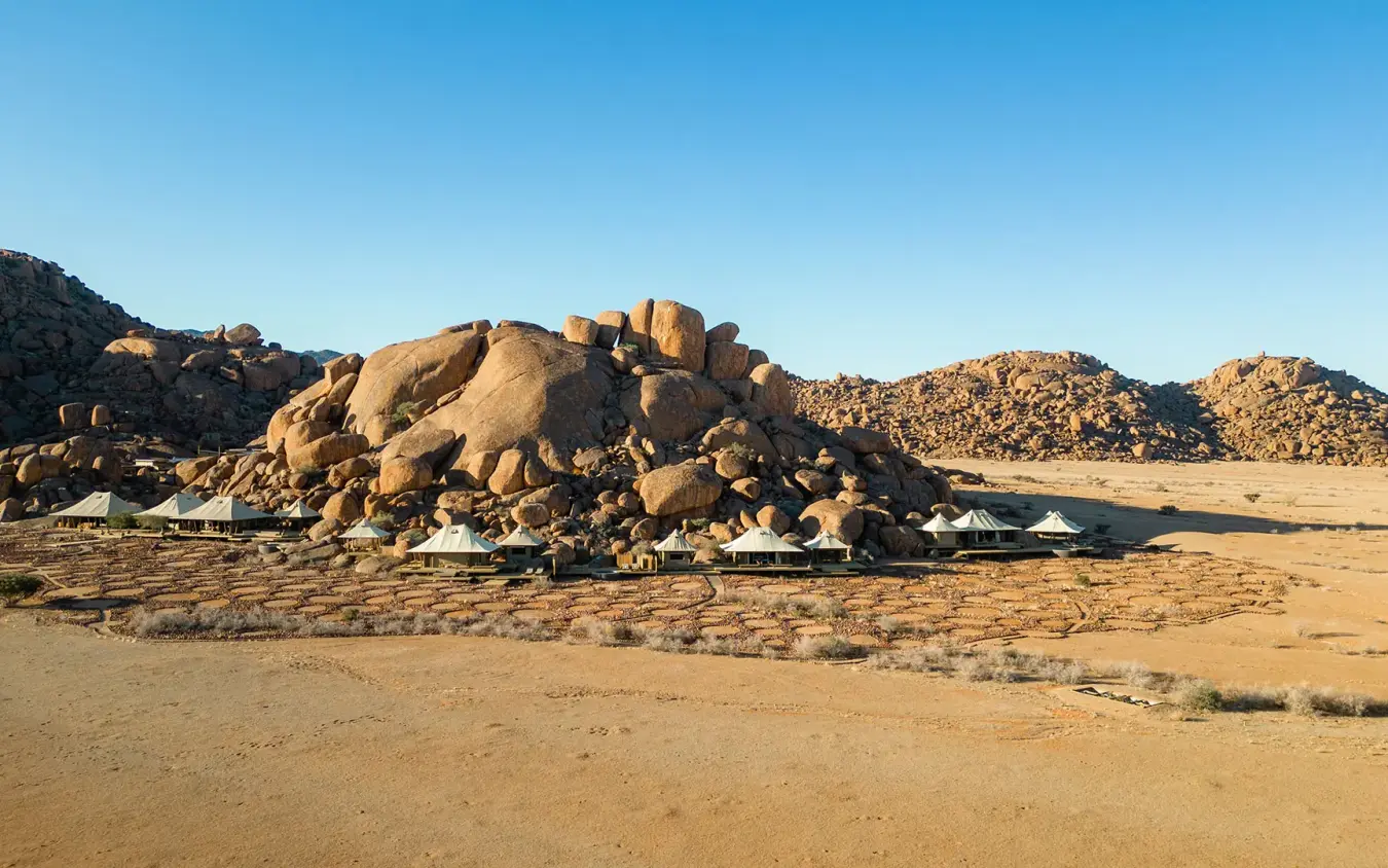 Boulder rock formations with safari lodge structures nestled below, Wolwedans Boulders Camp, NamibRand Private Reserve, Namibia