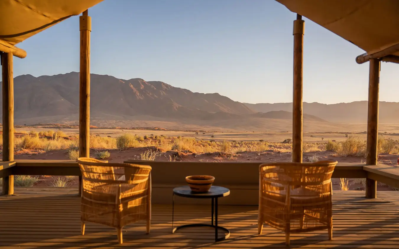 Wooden deck with wicker chairs overlooking desert landscape, Wolwedans Dune Camp, NamibRand Private Reserve, Namibia