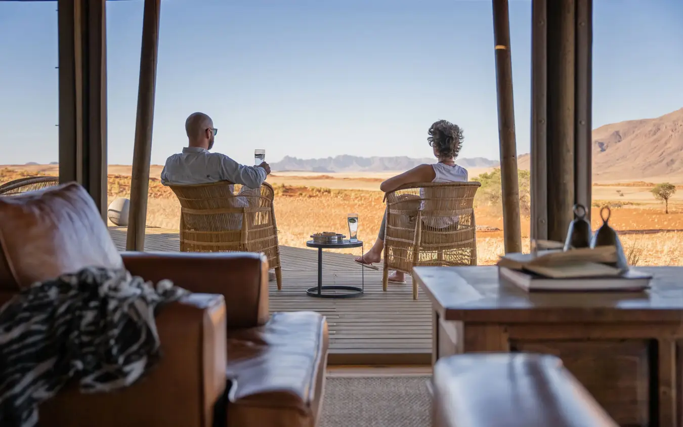 Guests relaxing on deck overlooking desert landscape, Wolwedans Dune Camp, NamibRand Private Reserve, Namibia