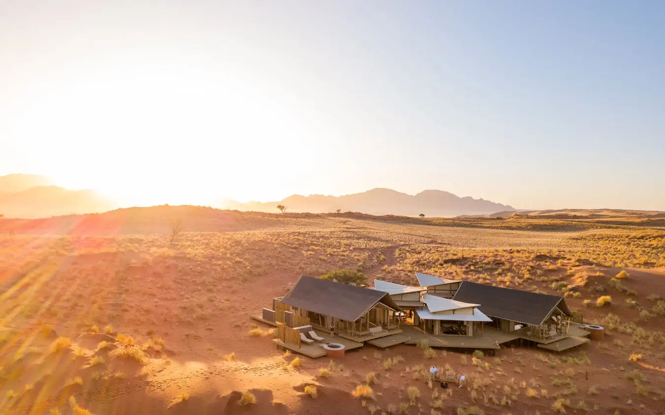 Desert lodge buildings at sunset with dune landscape, Wolwedans Dune Camp, NamibRand Private Reserve, Namibia