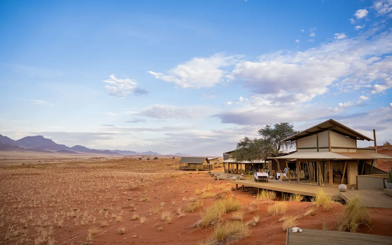 Desert lodge structures with red sand dunes and mountains, Wolwedans Dune Camp, NamibRand Private Reserve, Namibia