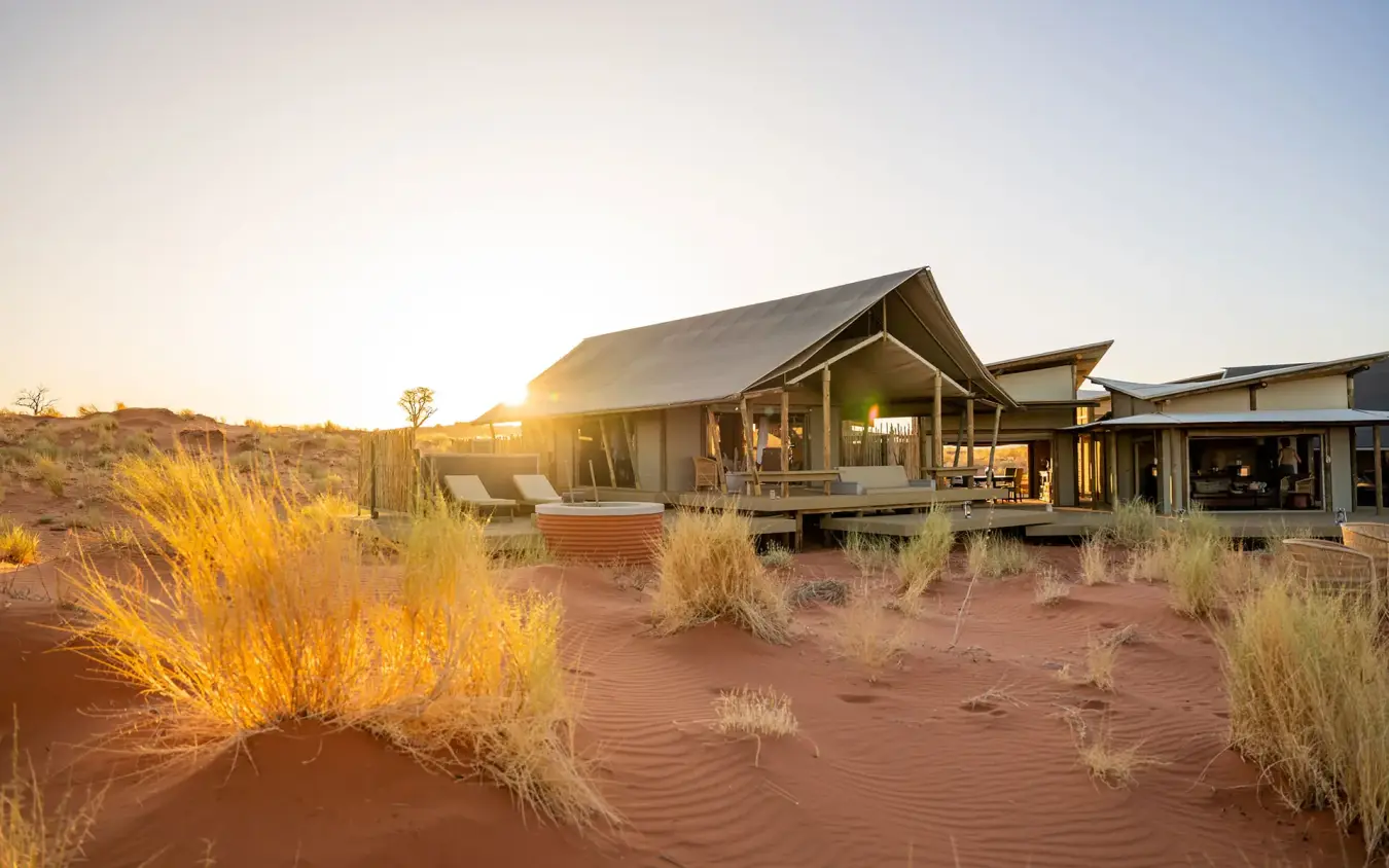 Desert lodge with thatched roof at golden hour sunset, Wolwedans Dune Camp, NamibRand Private Reserve, Namibia