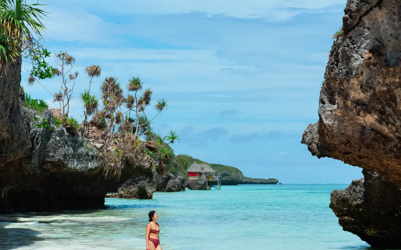 Woman wading in turquoise water between rock formations, Xanadu Villas, Zanzibar & Pemba, Tanzania