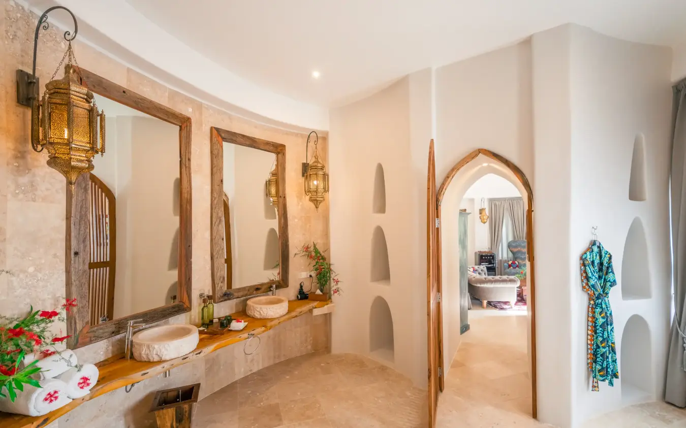 Spa bathroom with dual sinks, arched mirrors, and stone walls, Xanadu Villas, Zanzibar & Pemba, Tanzania