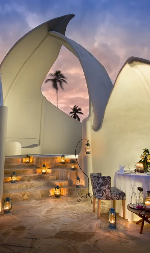 Illuminated white curved tent structure at dusk with palm trees, Xanadu Villas, Zanzibar & Pemba, Tanzania