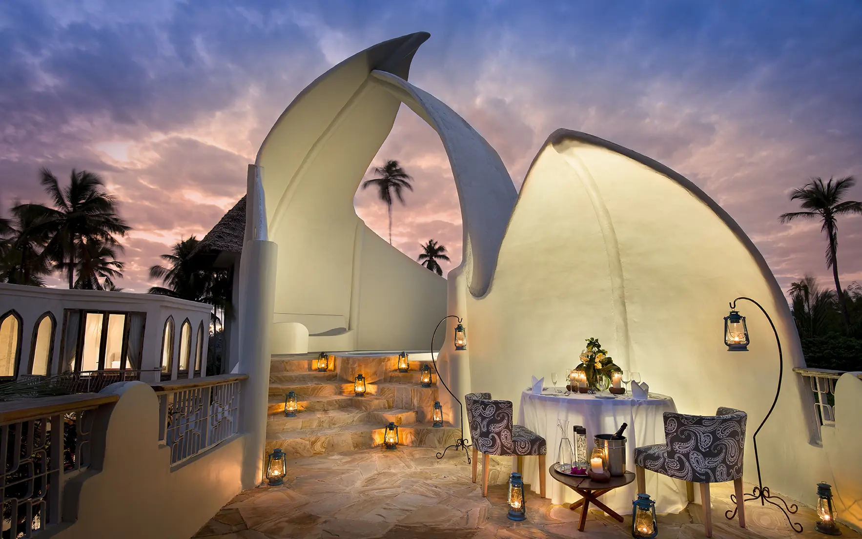 Illuminated white curved tent structure at dusk with palm trees, Xanadu Villas, Zanzibar & Pemba, Tanzania