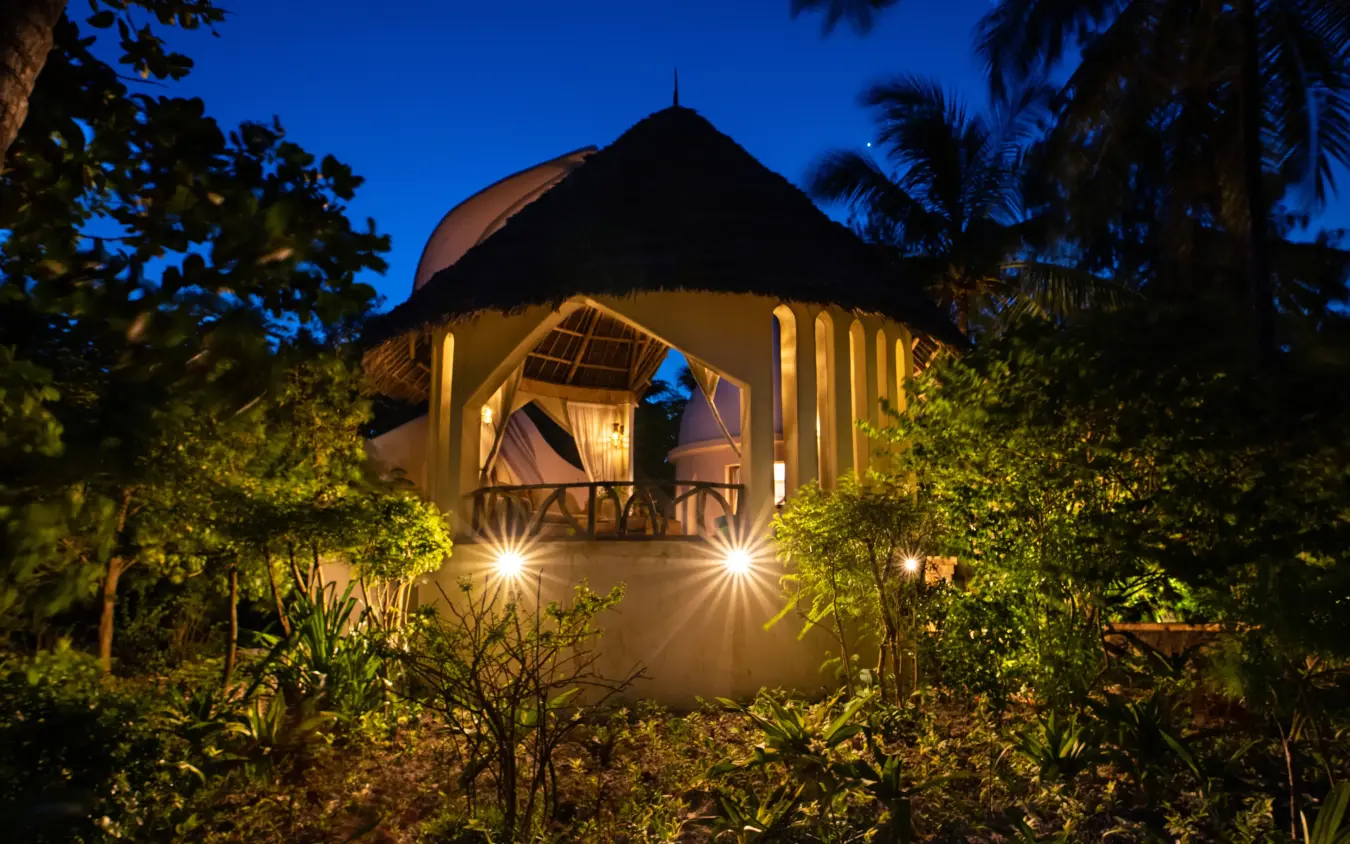 Illuminated thatched-roof pavilion surrounded by tropical vegetation at dusk, Xanadu Villas, Zanzibar & Pemba, Tanzania