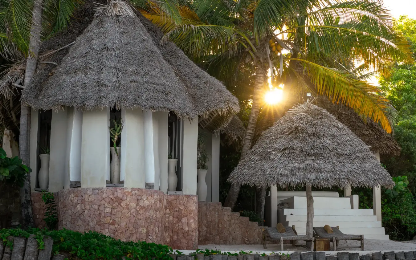 Thatched-roof spa bungalows among palm trees at sunset, Xanadu Villas, Zanzibar & Pemba, Tanzania