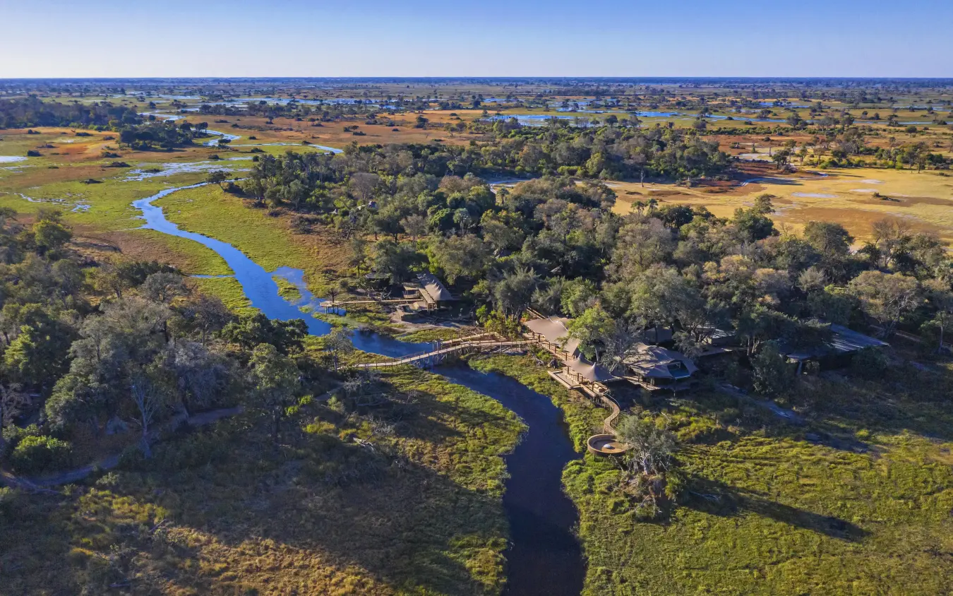 Winding river through floodplain with scattered trees and grassland, Xigera Lodge, The Okavango Delta, Botswana