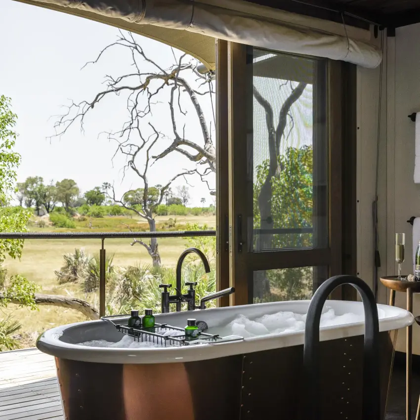 Freestanding bathtub with expansive savanna views through windows, Xigera Lodge, The Okavango Delta, Botswana