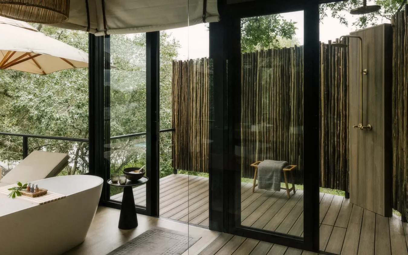 Outdoor bathroom with freestanding tub and wooden shower enclosure overlooking forest, Zambezi Sands, Victoria Falls, Zimbabwe