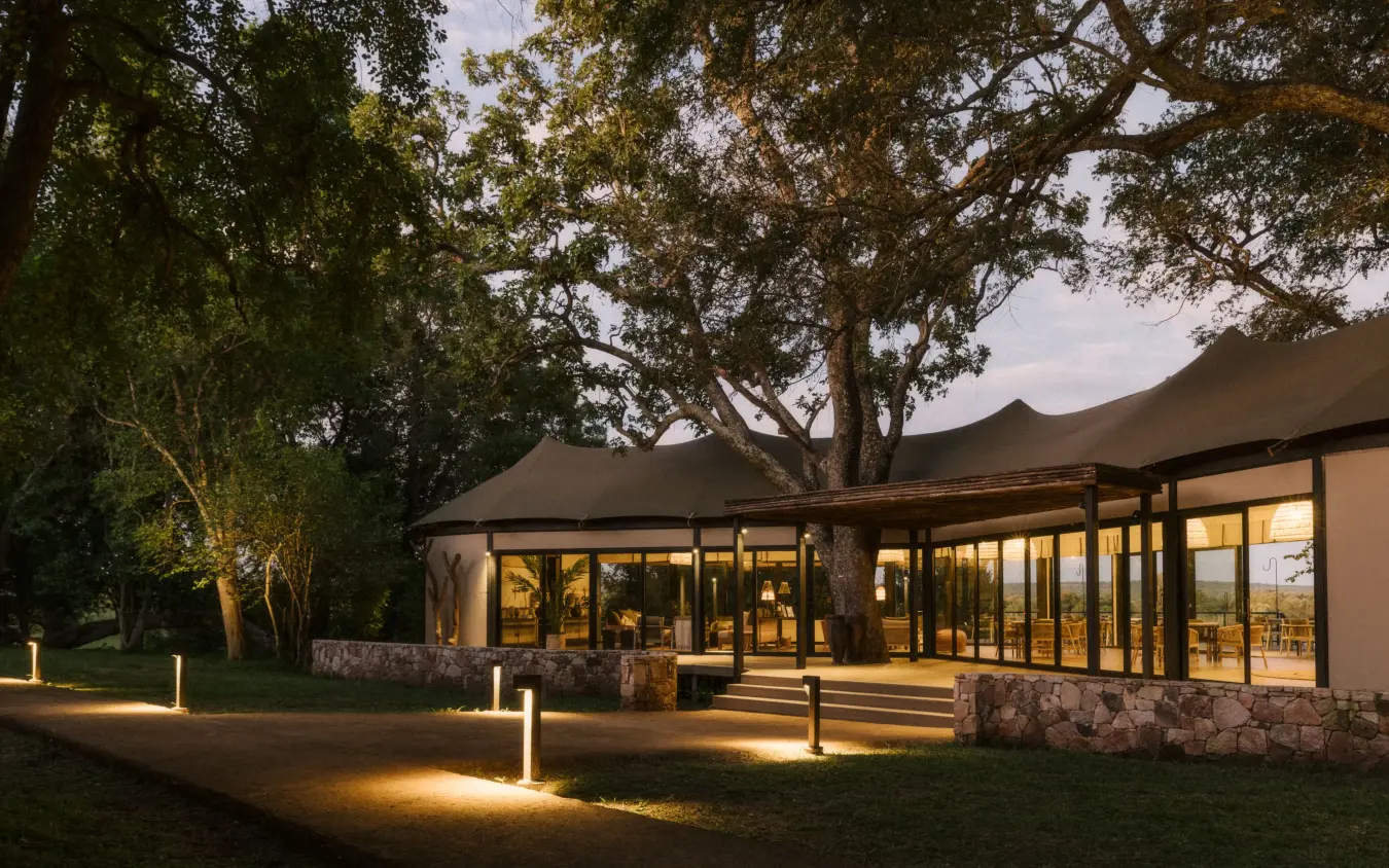 Modern lodge with illuminated pathways at dusk surrounded by native trees, Zambezi Sands, Victoria Falls, Zimbabwe