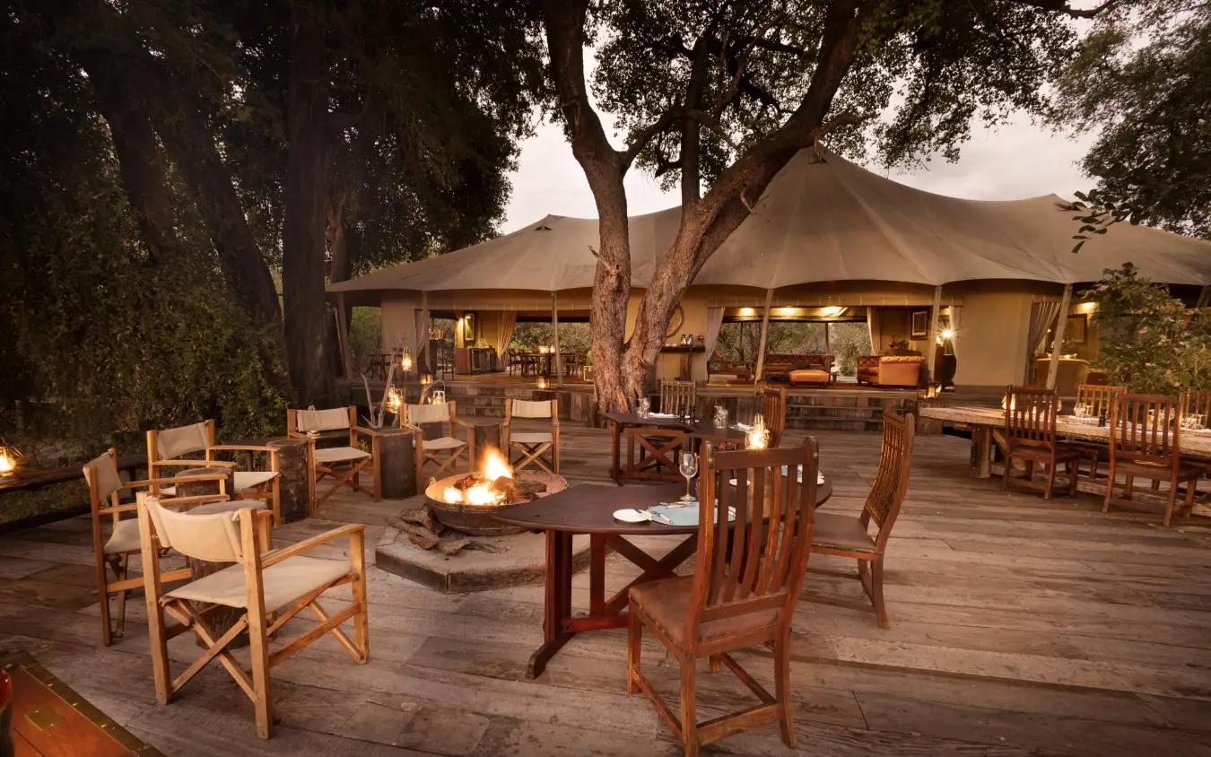 Safari lodge evening gathering area with fire pit and seating, Zarafa Camp, Selinda Reserve, Botswana