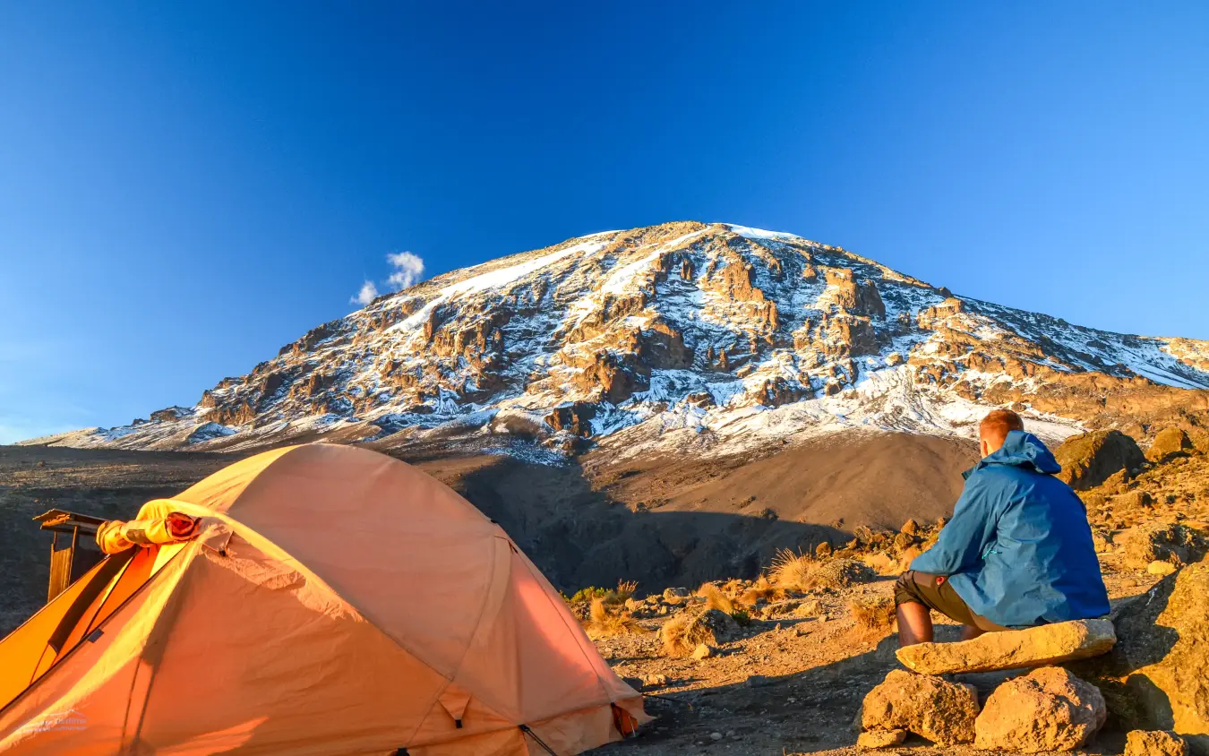 Climber camping at base of snow-capped mountain