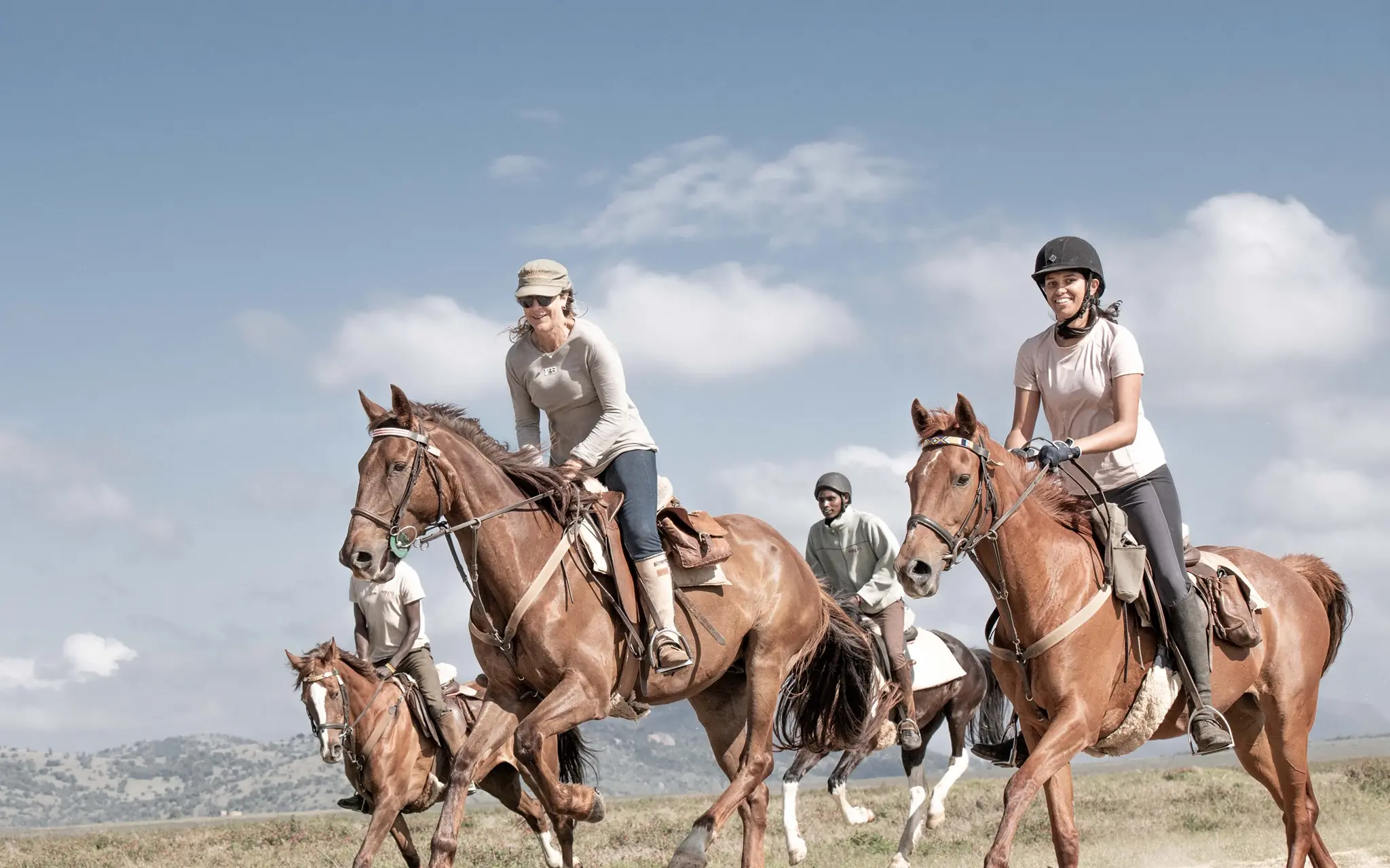 Guests riding horses across open grassland landscape, Borana Lodge, Laikipia Highlands, Kenya