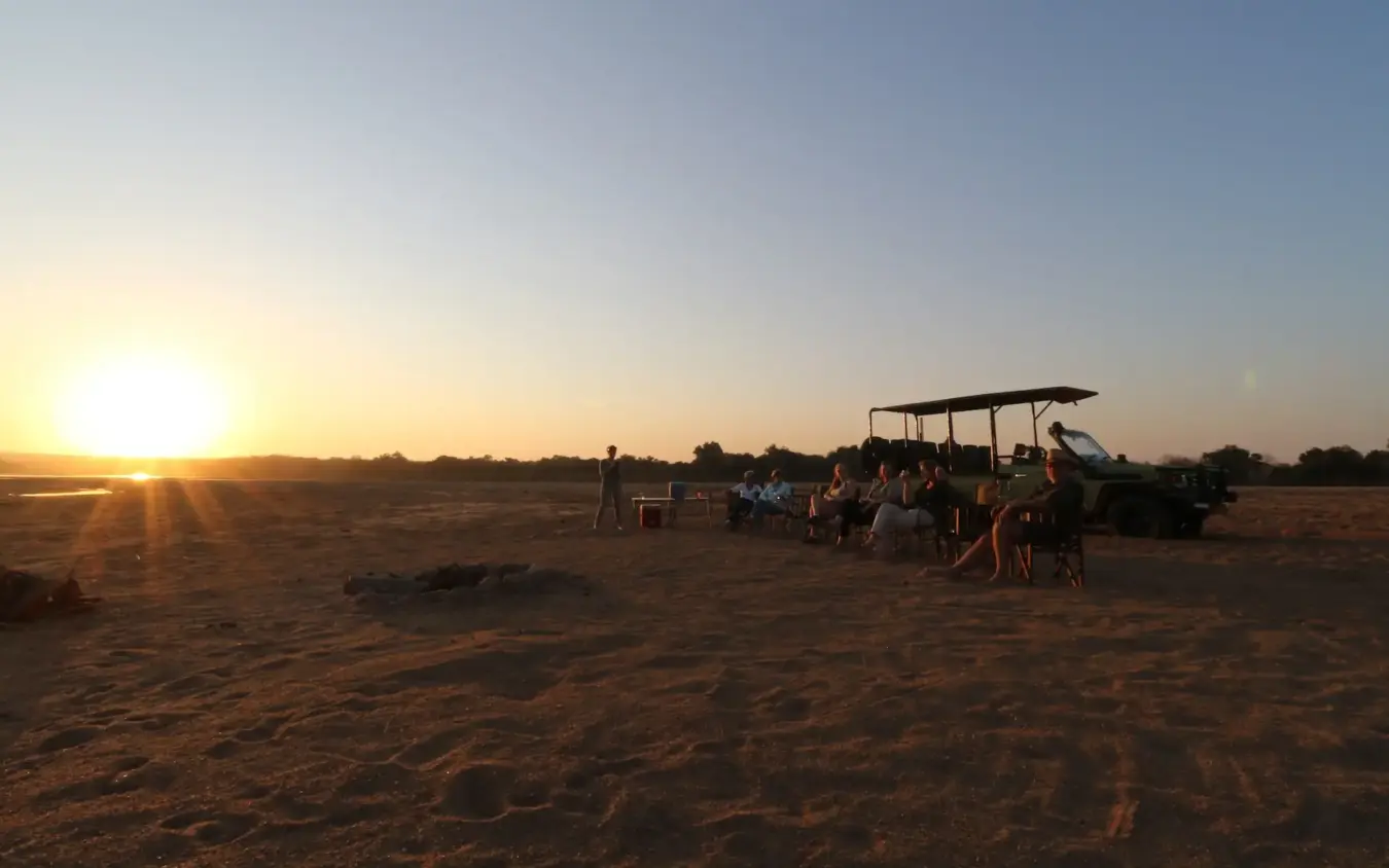 Safari vehicle with guests watching sunset on open plains, Chilo Gorge Safari Lodge, Gonarezhou & Malilangwe, Zimbabwe