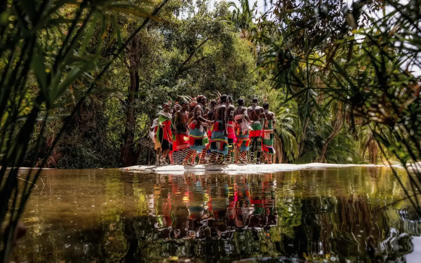 Group in red boat navigating narrow waterway through dense tropical vegetation, Desert Rose, Northern Kenya, Kenya