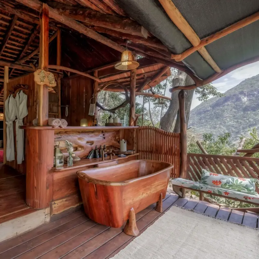 Wooden safari lodge bathroom with carved tub overlooking forested valley, Desert Rose, Northern Kenya, Kenya