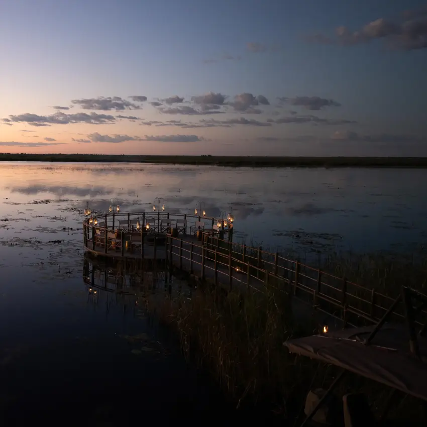 Wooden deck overlooking calm water at dusk with wildlife, DumaTau, Linyanti Wildlife Reserve, Botswana