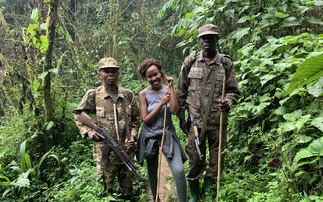 Armed guides with hiker on jungle trail through dense forest vegetation
