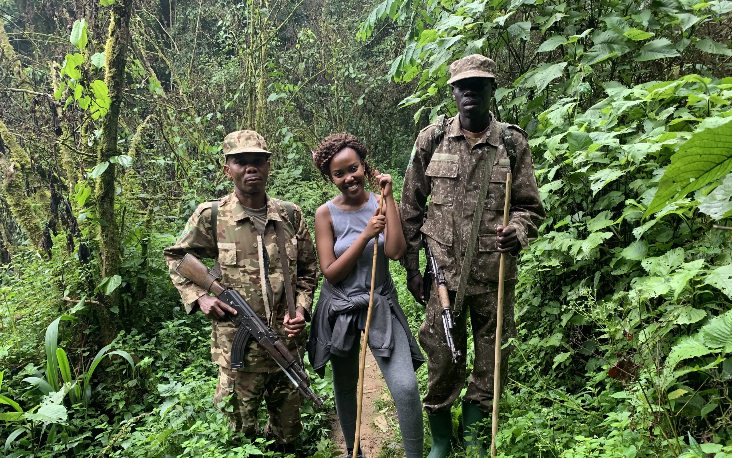 Armed guides with hiker on jungle trail through dense forest vegetation