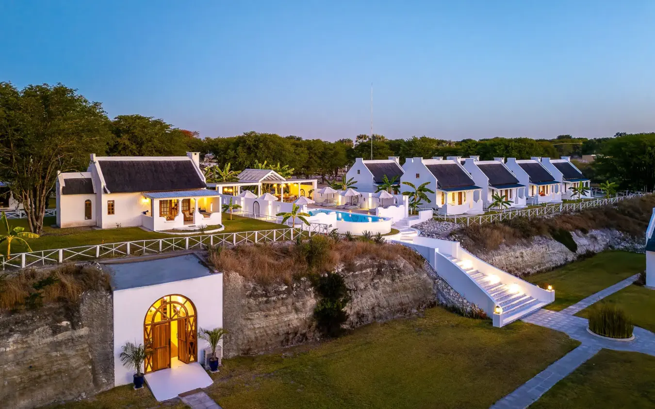 Luxury white cottages with pool overlooking coastal cliffs at dusk, Grays Eden, Maun, Botswana