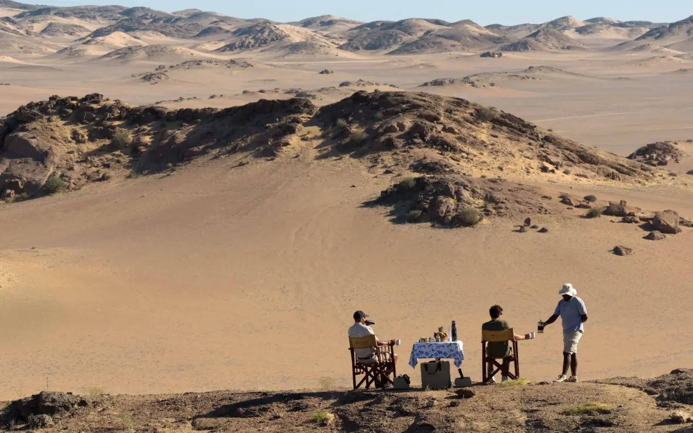 Guests enjoying picnic lunch in desert landscape with mountain views, Hoanib Elephant Camp, Skeleton Coast, Namibia
