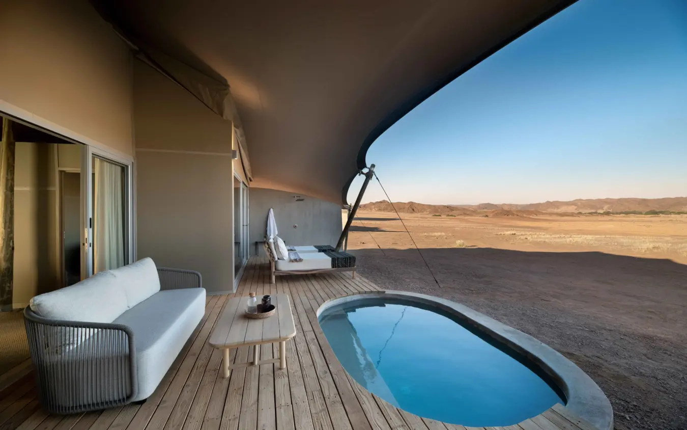 Luxury tent deck with plunge pool overlooking arid plains at dusk, Hoanib Elephant Camp, Skeleton Coast, Namibia