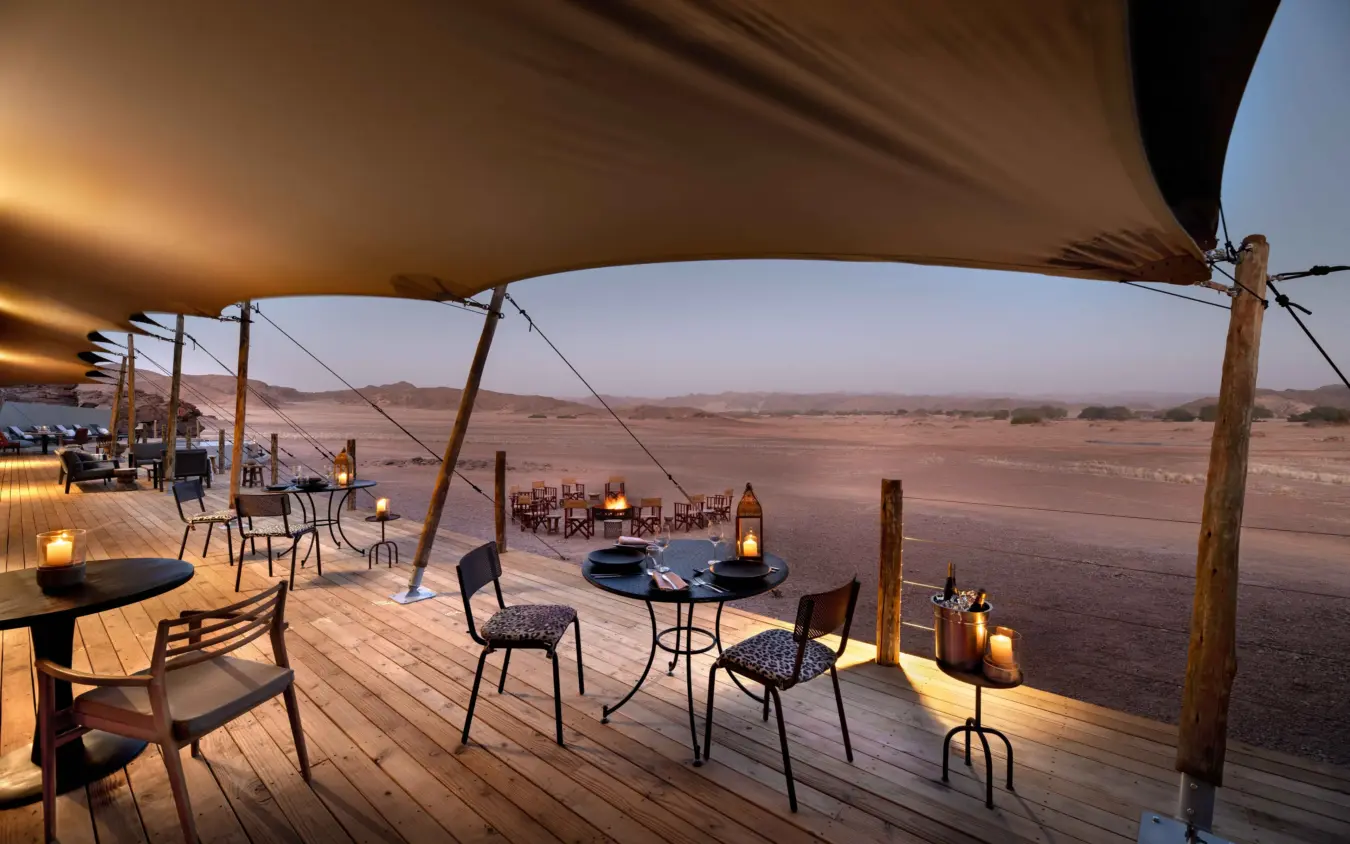 Elevated wooden deck with lounge seating overlooking vast desert landscape at dusk, Hoanib Elephant Camp, Skeleton Coast, Namibia