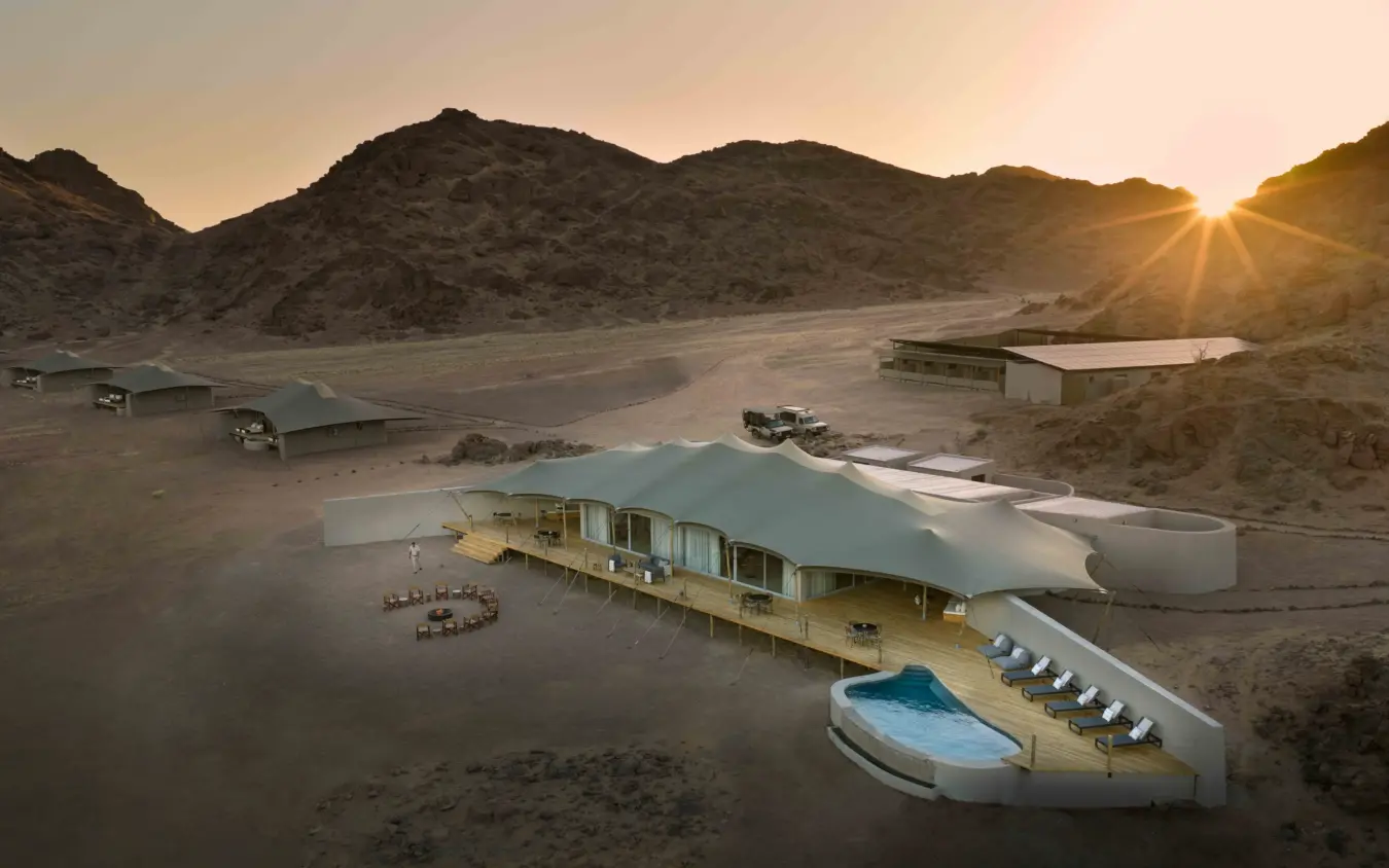 Desert lodge with infinity pool at sunset surrounded by mountains, Hoanib Elephant Camp, Skeleton Coast, Namibia