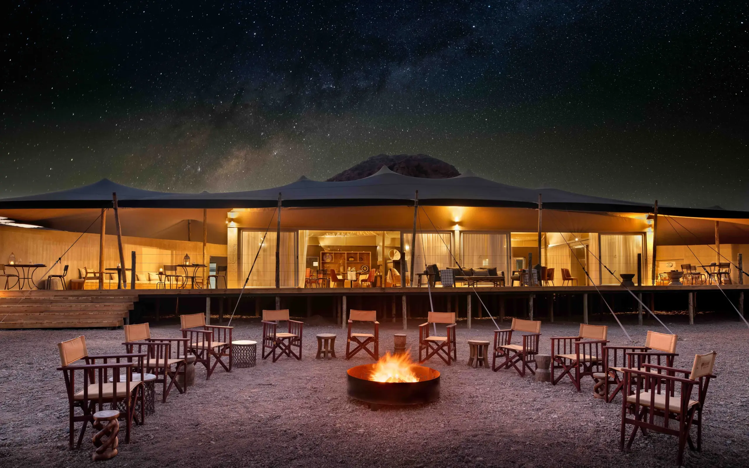 Luxury safari camp with illuminated tent and firepit under starry night sky, Hoanib Elephant Camp, Skeleton Coast, Namibia