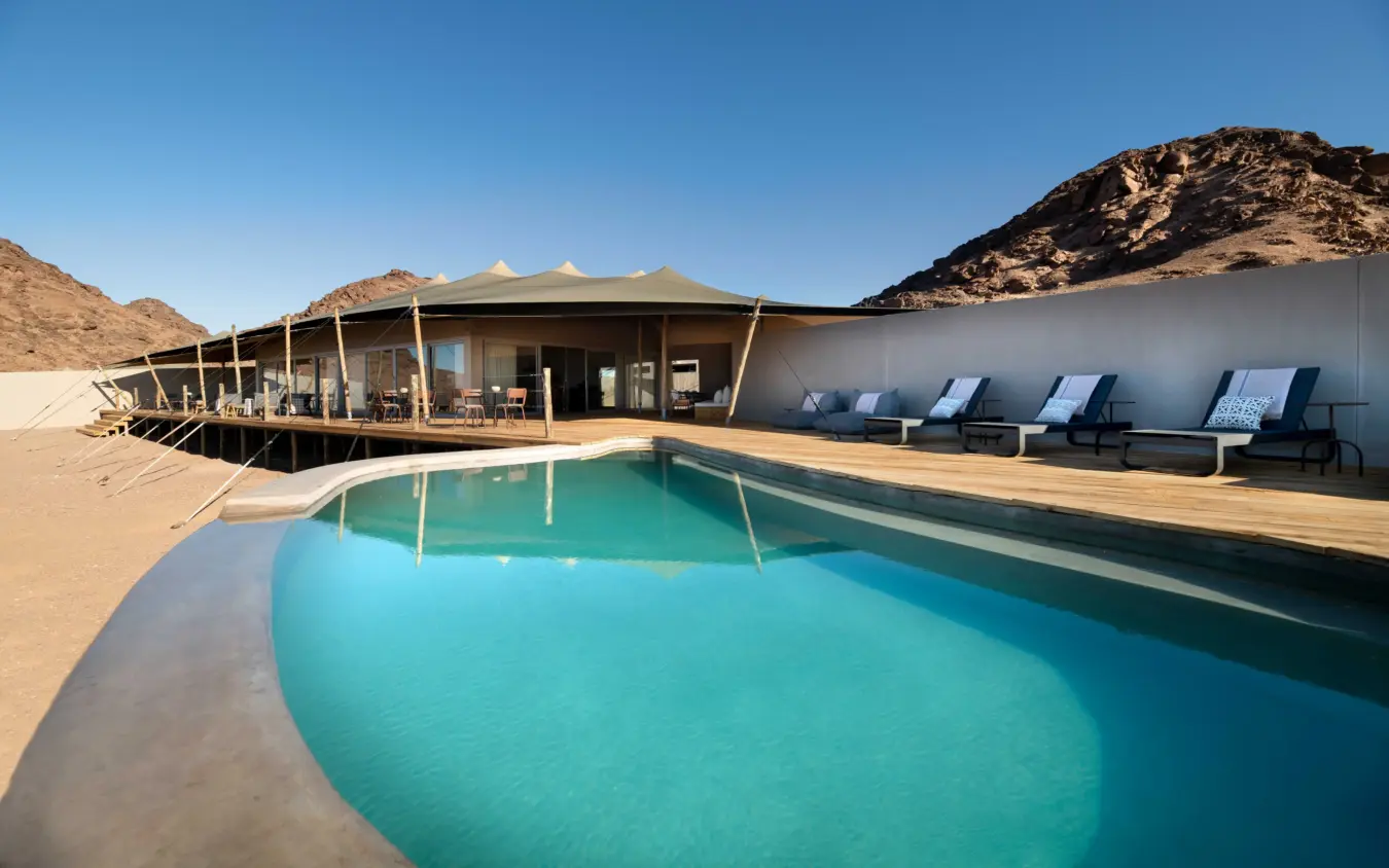 Luxury pool pavilion with loungers overlooking desert mountains, Hoanib Elephant Camp, Skeleton Coast, Namibia