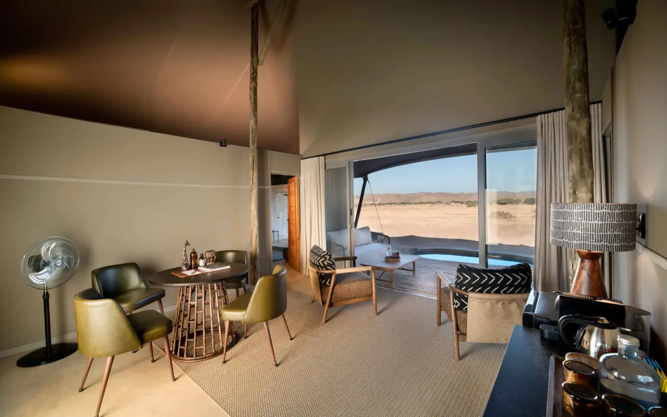 Modern safari lodge interior with desert landscape view through floor-to-ceiling windows, Hoanib Elephant Camp, Skeleton Coast, Namibia