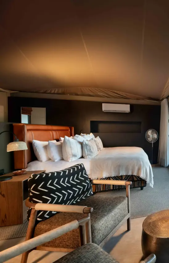 Luxury safari tent bedroom interior with orange leather headboard and canvas ceiling, Hoanib Elephant Camp, Skeleton Coast, Namibia